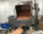 Ein Hebelift bei der Lebensmittelverarbeitung, der Shrimps auf ein Fließband auskippt.