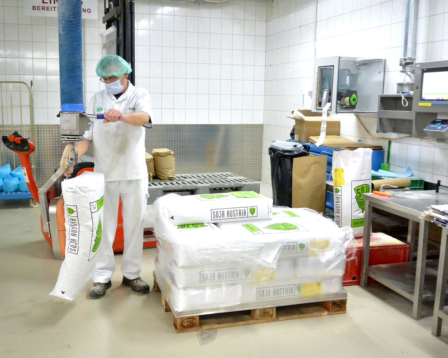 Sackhandling in der produzierenden Lebensmittelindustrie bei dem ein Mann einen Vakuumheber bedient.